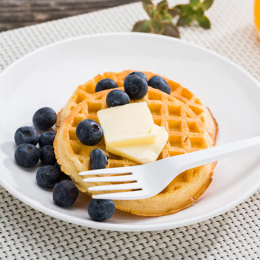 Waffle with blueberries and butter on a white plate with a Ecoz white compostable fork. 